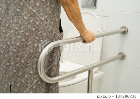 Asian elderly woman use toilet security support rail in bathroom. 137296733