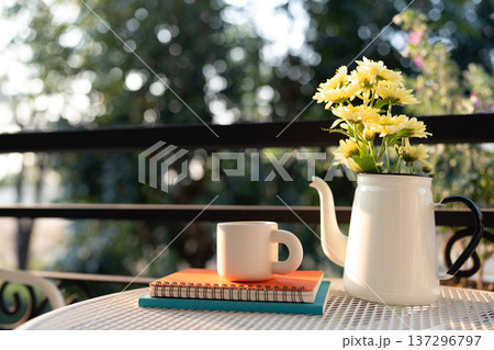 White coffee cup and stack of notebook and pot of yellow Chrysanthemum flowers, balcony nature view 137296797