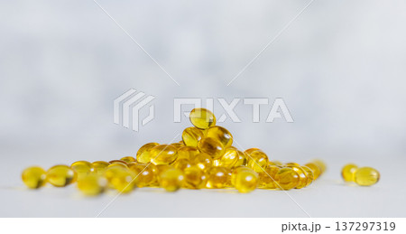 Yellow softgel scattered from transparent jar on greige ston, Nutritional supplements or vitamins 137297319