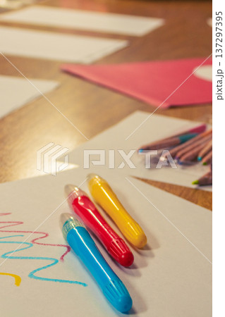 Three colorful red, blue and yellow crayons on white paper with playful scribbles, Three colorful red, blue and yellow crayons on white paper with playful scribbles, 137297395