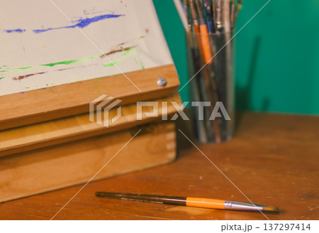 an orange paintbrush, arranged on a warm wooden table in an artist's studio, symbolizing creativity 137297414