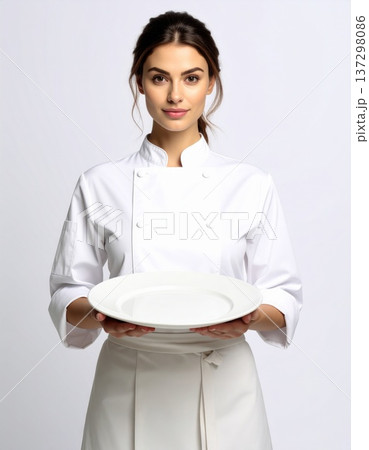Woman in White Chef Uniform Holding Empty White Plate on White Backdrop 137298086