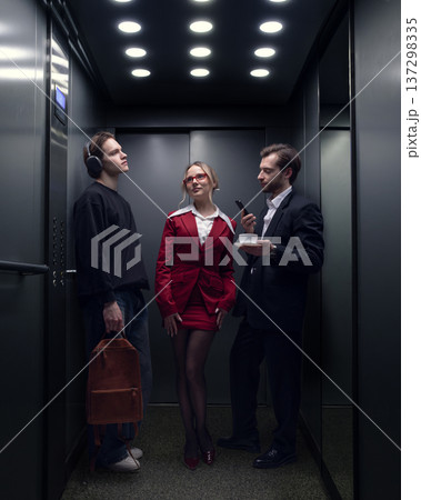 Three professionals standing together inside modern office elevator in business building 137298335