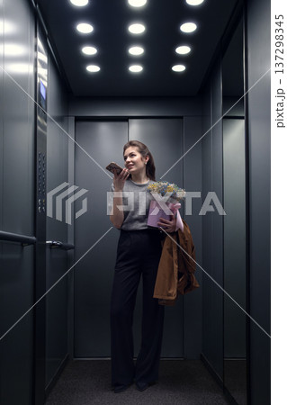 Young woman recording voice message on smartphone while holding bouquet. Young woman recording voice message on smartphone while holding bouquet. 137298345