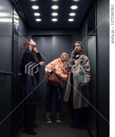 Three young women using elevator during busy city workday. Three young women using elevator during busy city workday. 137298363