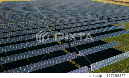 Aerial drone close view of solar power plant with long rows of photovoltaic panels generating renewable energy 137298375