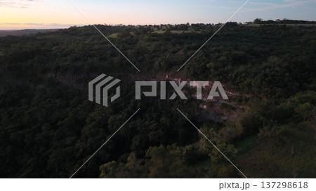 Cassilandia, Mato Grosso do Sul, Brazil - 04 05 2024. Drone aerial view of Cachoeira do Socorro waterfall flowing over a rocky cliff surrounded by dense forest vegetation during early morning light. Cassilandia, Mato Grosso do Sul, Brazil - 04 05 2024. Drone aerial view of Cachoeira do Socorro waterfall flowing over a rocky cliff surrounded by dense forest vegetation during early morning light. 137298618