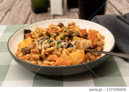 Hearty beef stew with pasta, potatoes, and carrots 137300008