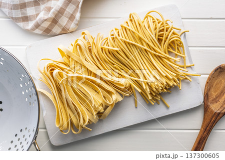 Fresh pasta ready for cooking, showing strands of fettuccine and bigoli set on white table. 137300605
