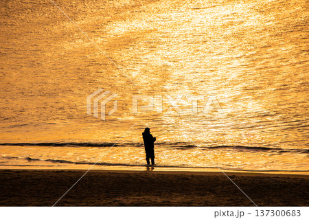 太陽に照らされ輝く海と釣り人のシルエット 137300683