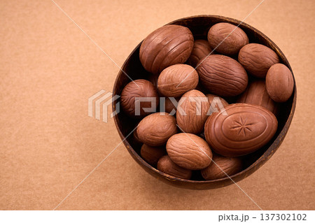 Chocolate easter eggs filling coconut bowl on brown background Chocolate easter eggs filling coconut bowl on brown background 137302102