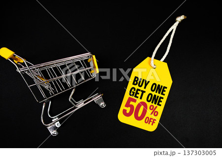 Mini Trolley Shopping Cart and price tag with message "Buy One, Get One 50% Off" on black background 137303005