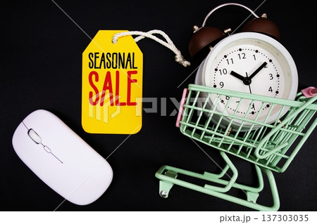 Seasonal Sale text with price tag, optical mouse, trolly cart and alarm clock on black background, Shopping Online Concept Seasonal Sale text with price tag, optical mouse, trolly cart and alarm clock on black background, Shopping Online Concept 137303035