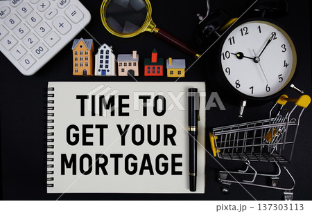 Notepad with the phrase "Time To Get Your Mortgage" surrounded by a pen, mini trolley shopping cart, magnifying glass, clock, and house model Notepad with the phrase "Time To Get Your Mortgage" surrounded by a pen, mini trolley shopping cart, magnifying glass, clock, and house model 137303113