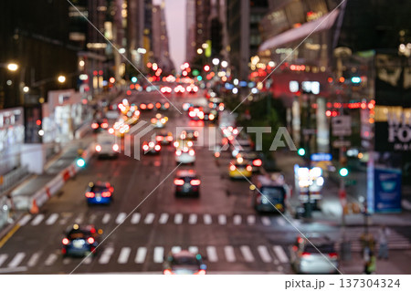 Blurred traffic lights glow along a busy Manhattan street at night. The cityscape captures movement, transportation, and urban energy in New York City. 137304324