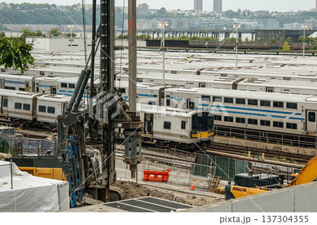 Rows of commuter train cars are parked along multiple tracks in a large Manhattan rail yard. Transportation infrastructure supports daily urban travel across New York City. Rows of commuter train cars are parked along multiple tracks in a large Manhattan rail yard. Transportation infrastructure supports daily urban travel across New York City. 137304355