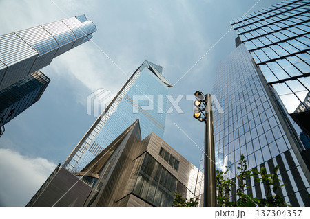 Reflective glass skyscrapers rise into a clear sky beside a modern street light in Manhattan, New York City. Contemporary urban architecture defines the downtown skyline. 137304357