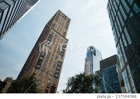 Brick residential tower and modern glass skyscrapers rising against the sky in Manhattan, New York City. Urban architecture highlights the contrast between classic and contemporary design. 137304366