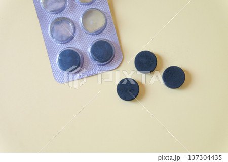 Activated carbon in tablet pill on a light background. Activated carbon in tablet pill on a light background. 137304435