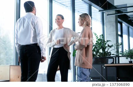 Three people are standing in a room, one of them is wearing a brown sweater 137306890