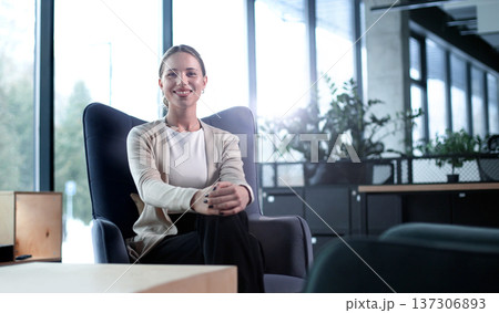 A woman sits in a chair in a room with a potted plant in front of her A woman sits in a chair in a room with a potted plant in front of her 137306893