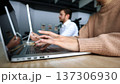 A woman is typing on a laptop while a man looks on 137306930