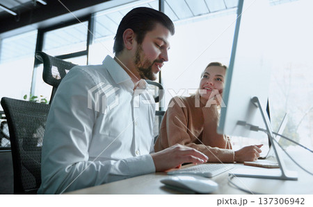 A man and a woman are looking at a computer monitor 137306942