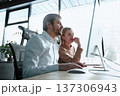 A man and a woman are looking at a computer monitor 137306943