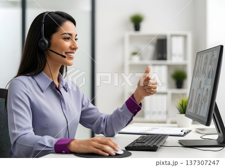 Smiling Customer Service Representative with Headset Giving Thumbs Up During Virtual Meeting 137307247