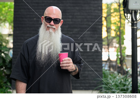Bald Man with Long White Beard Holding Coffee Outdoors 137308608