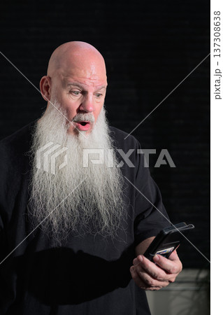 Bald Bearded Man Reacting to Mobile with Surprise and Shock 137308638