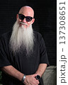 Portrait of a bald man with a long white beard wearing sunglasses against a dark background 137308651