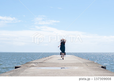 青空と青い海と走る麦わら帽子の女性 137309008