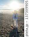 A young woman hugs her Cavalier King Charles Spaniel on the beach at sunset. Warm light, waves, and smiles capture a peaceful, joyful moment of connection and relaxation. 137309905