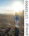 A young woman hugs her Cavalier King Charles Spaniel on the beach at sunset. Warm light, waves, and smiles capture a peaceful, joyful moment of connection and relaxation. 137309906