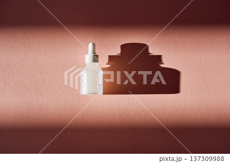 Serum bottle casting shadow on pink background Serum bottle casting shadow on pink background 137309988