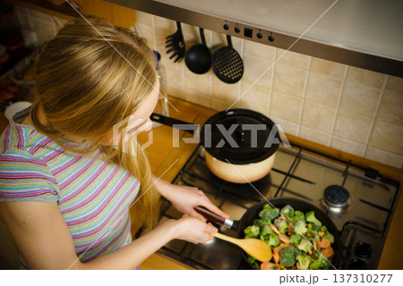 Woman cooking stir fry frozen vegetable on pan Woman cooking stir fry frozen vegetable on pan 137310277