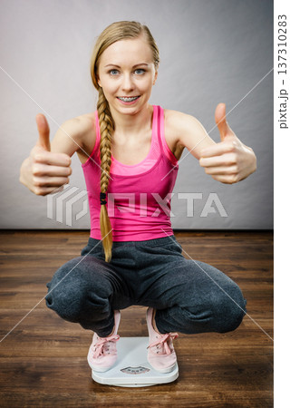 Teenage woman on bathroom scale machine Teenage woman on bathroom scale machine 137310283