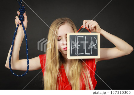 Suicidal woman holding help sign next to rope Suicidal woman holding help sign next to rope 137310300