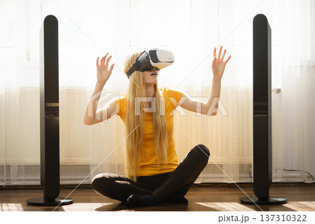 Girl wearing virtual reality goggles at home Girl wearing virtual reality goggles at home 137310322