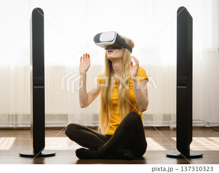 Girl wearing virtual reality goggles at home Girl wearing virtual reality goggles at home 137310323