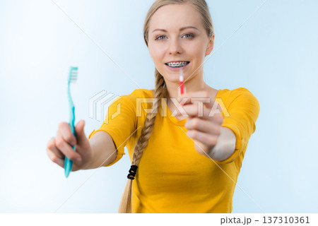Woman smiling cleaning teeth with braces 137310361