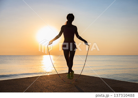 Fit woman jumping rope at the beach during summer vacation 137310488