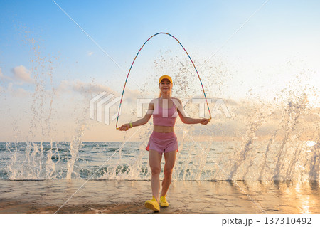 Fit woman jumping rope at the beach during summer vacation Fit woman jumping rope at the beach during summer vacation 137310492