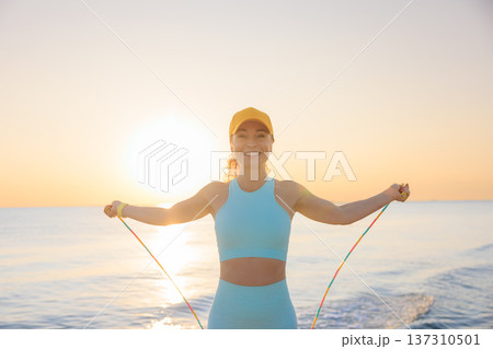 Fit woman jumping rope at the beach during summer vacation 137310501