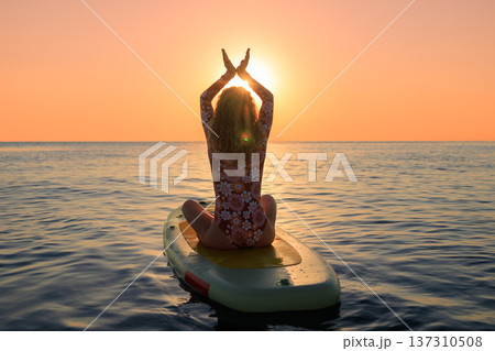 Young woman walking on sup board by the sea during summer vacation Young woman walking on sup board by the sea during summer vacation 137310508