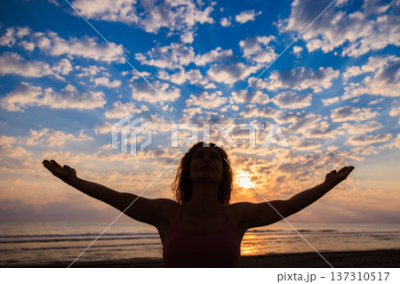 Happy woman enjoying sunrise at the beach during summer vacation Happy woman enjoying sunrise at the beach during summer vacation 137310517