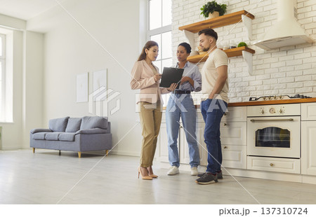 Young happy couple discussing contract with female realtor agent looking through the documents Young happy couple discussing contract with female realtor agent looking through the documents 137310724
