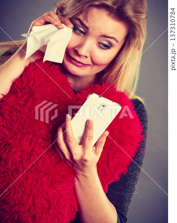 Sad heartbroken woman looking at her phone 137310784