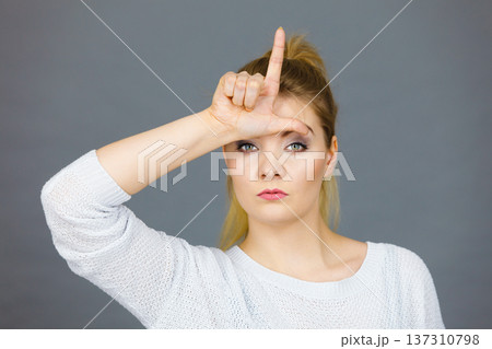 Woman showing loser gesture with L on forehead Woman showing loser gesture with L on forehead 137310798